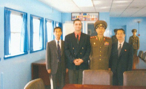 A photograph of John Paul Cupp, Chairman of the U.S Songun Politics Study Group taken at the demilitarized zone on the border with South Korea from the North Korean side. Photo is with a North Korean military officer in the neutral zone during a 2007 trip Cupp made to North Korea as an official guest of Pyongyang